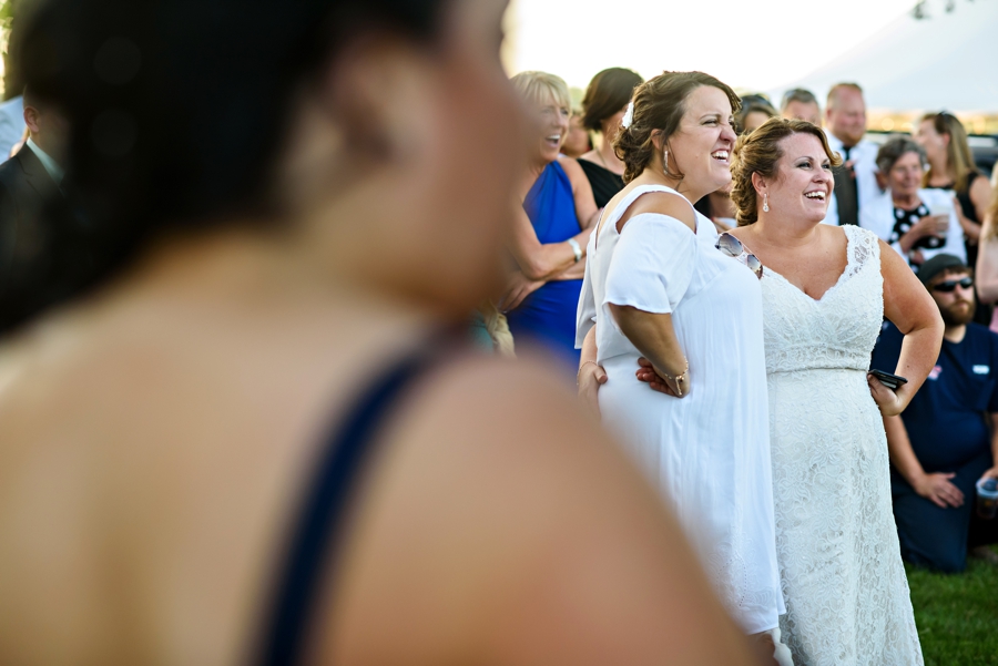 Two brides hold each other during their wedding as speeches are given.